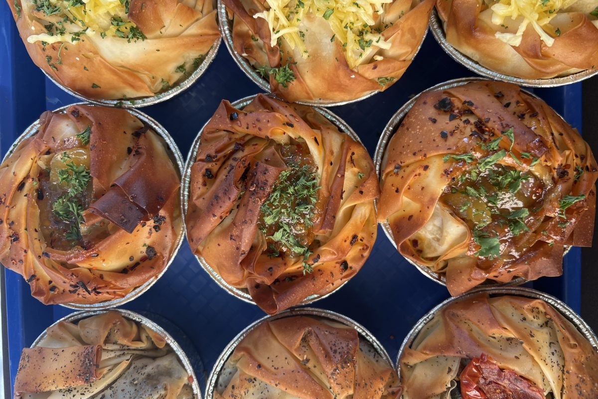 A tray of assorted filo pastry pies with crisp, golden layers and various herb or glaze toppings.