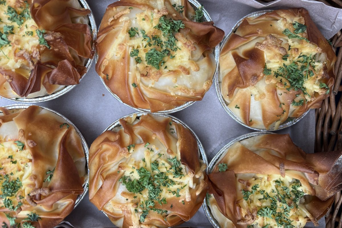 A tray of golden filo pastry pies with crisp edges and sprinkled with chopped herbs.