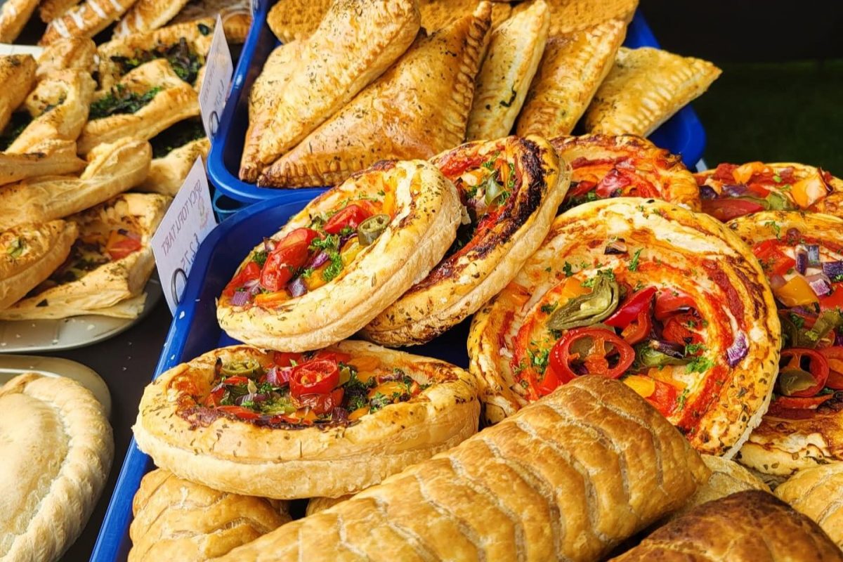 Photo of vegan munchies savoury tarts and bakes on a market stall.