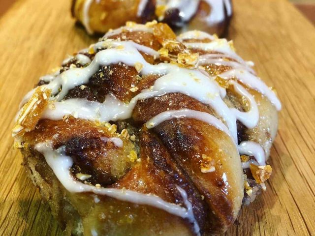 Freshly baked artisan cinnamon-style bun drizzled with icing and handmade by The Burnt Squash Kitchen & Bakery in Dorset.